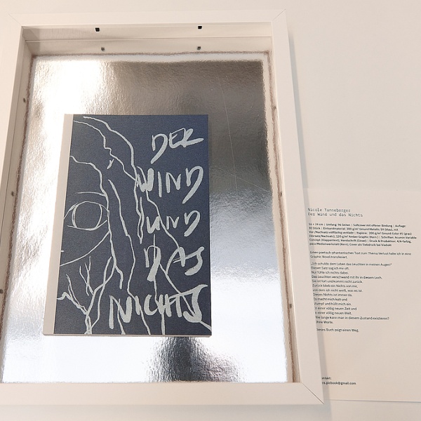 Ein Schwarzes Buch mit einem Mädchen und den Worten "Der Wind und das Nichts"