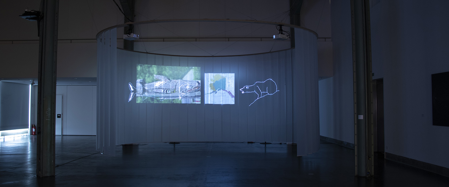 Projektionen auf einem Vorhang in einer Lagerhalle