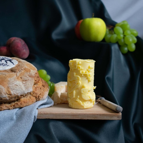 Käse, Weintrauben, Brot und ein Messer auf einem Holzbrett