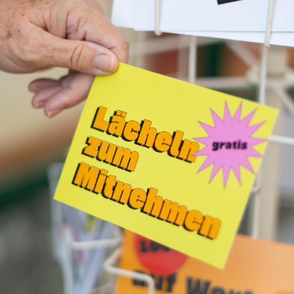 Ein Kärtchen mit der Aufschrift "Lächeln zum Mitnehmen"