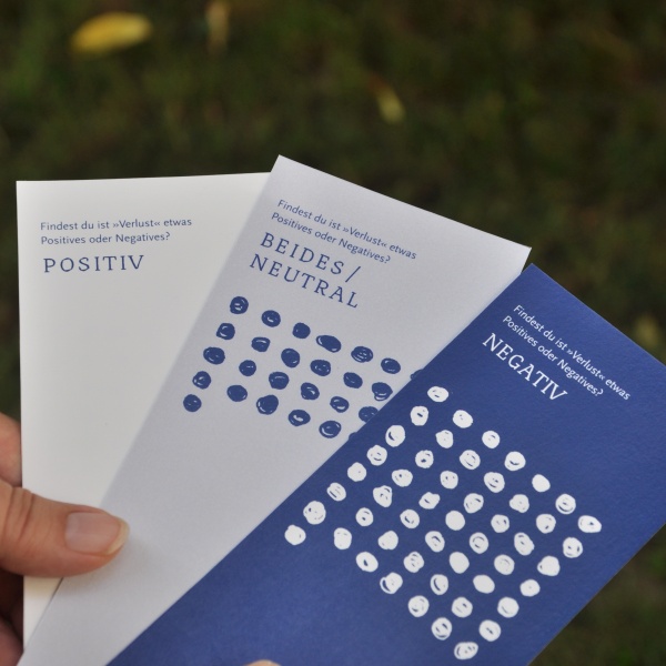 Drei Umfragekärtchen die die Frage „Ist Verlust etwas Positives oder Negatives" statistisch künstlerisch darstellen