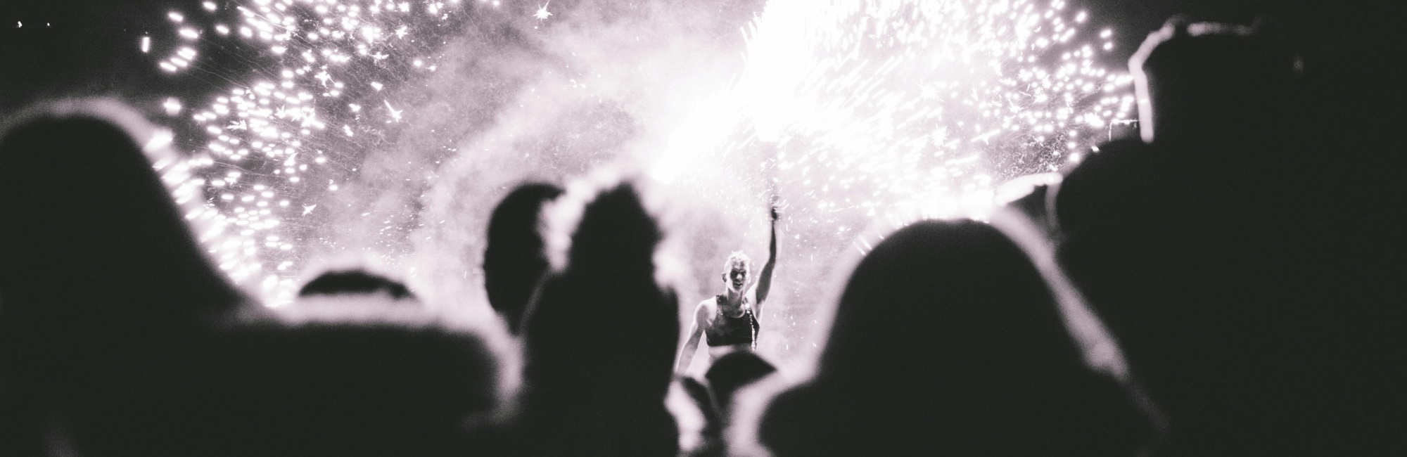 Ein Live-Konzert mit mit B&uuml;hnenfeuerwerk. Schwarz-Wei&szlig; Bild durch die Menge fotografiert.