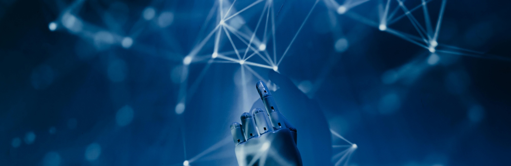 Roboterhand zeigt mit dem Zeigefinger an den oberen Bildrand, der Hintergrund ist dunkel mit dr&uuml;berlaufenden futuristischen blauen Lichtnetzen