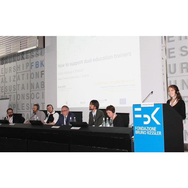 7 Personen sitzen an einem Tisch und bereden etwas