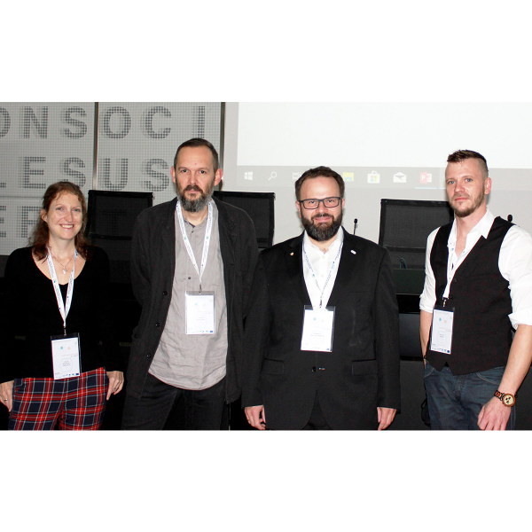 Eine Frau und drei M&auml;nner l&auml;cheln in die Kamera