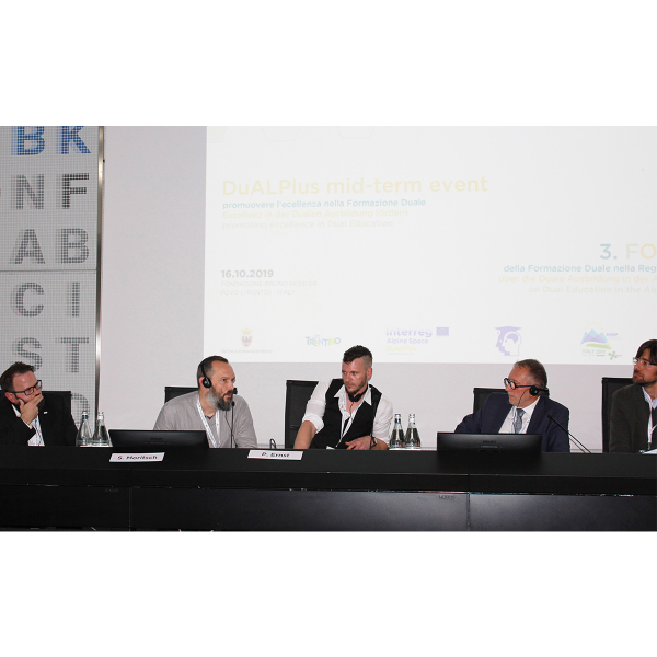 Fünf Männer sitzen an einem Tisch und diskutieren etwas