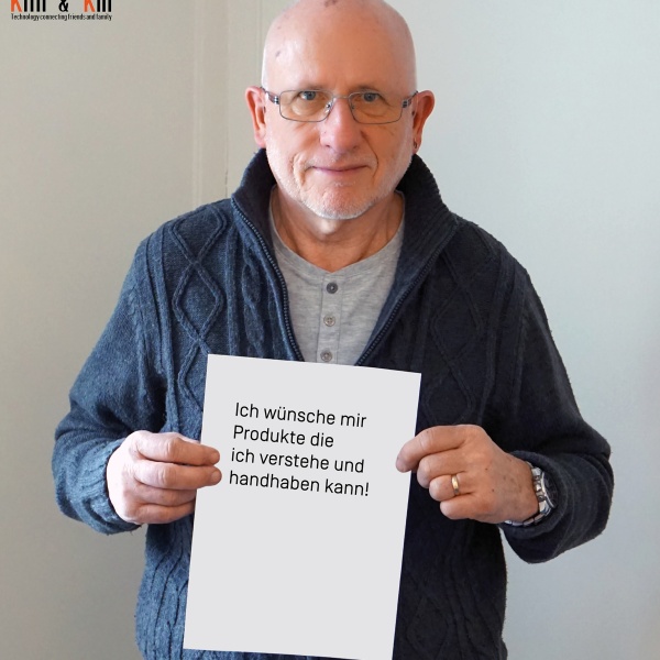 Mann hält ein Blatt, auf dem steht "Ich wünsche mir Produkte, die ich verstehe und handhaben kann!"