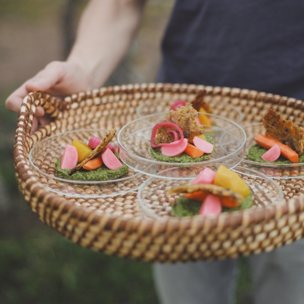 Tablett aus Korbgeflecht mit kleinen Essensportionen auf Glastellern