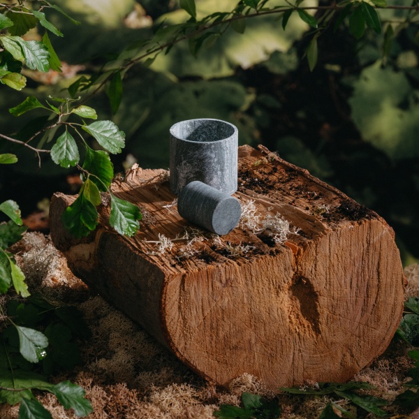 M&ouml;rser aus Stein auf einem l&auml;ngs halbierten Baumstamm