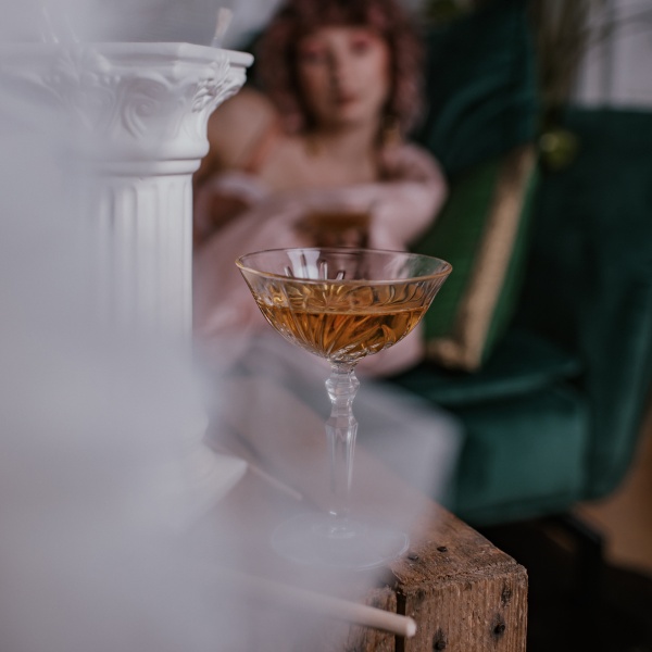 Getränk in Champagnerglas mit Frau im Hintergrund